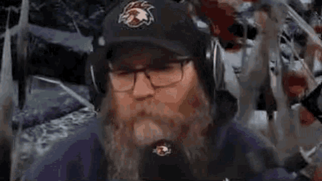 a man with a beard is wearing a hat and headphones .