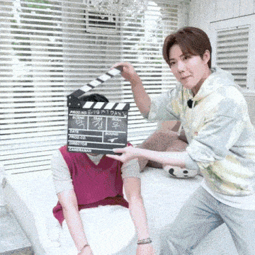 a man is holding a clapper board that says ' production ' on it