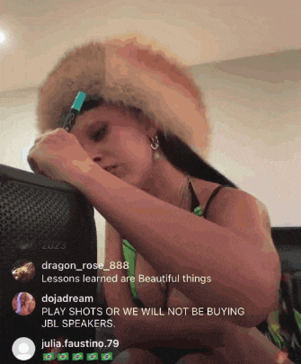 a woman wearing a fur hat is writing on a piece of paper in front of jbl speakers