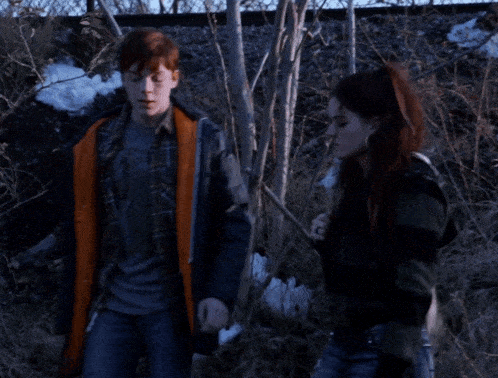 a boy and a girl are standing next to each other and the girl has red hair