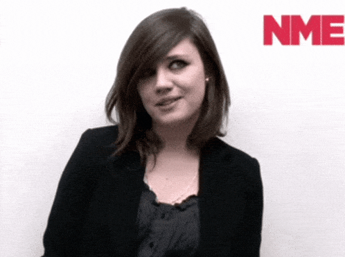 a woman stands in front of a white wall with nmf in red