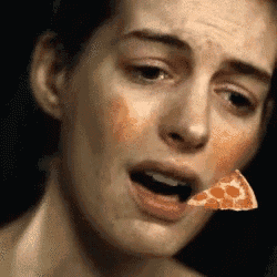 a woman is eating a slice of pizza with her mouth open