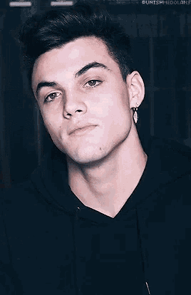 a close up of a young man wearing a black hoodie