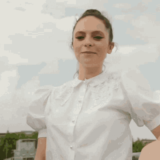 a woman in a white shirt is sticking her tongue out while giving the middle finger