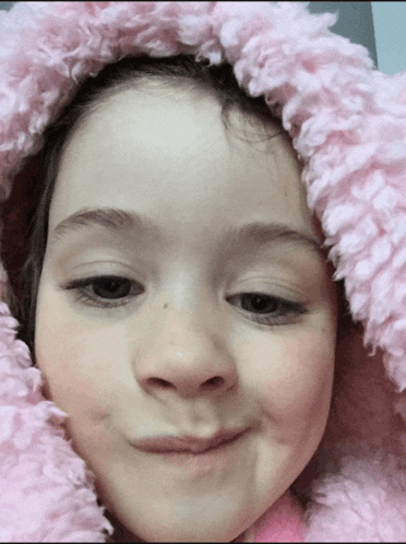 a little girl wearing a pink furry hooded jacket
