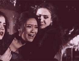 two women are hugging each other in a dark room and one of them is crying .