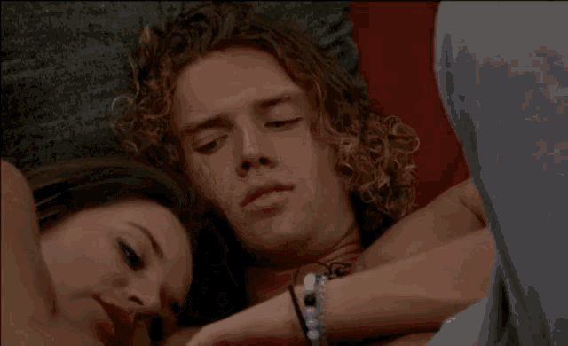 a shirtless man with curly hair is smiling