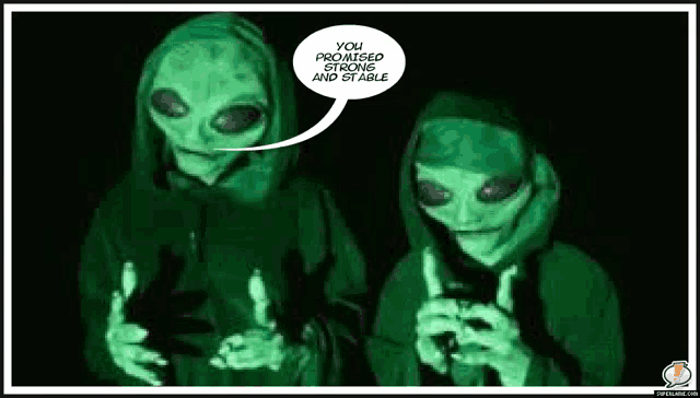two aliens are standing next to each other in a dark room talking to each other .
