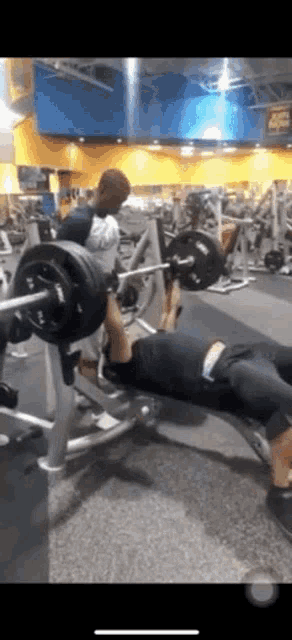 a man is bench pressing a barbell in a gym .