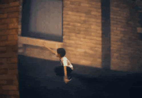 a person is jumping over a brick wall with their arm outstretched