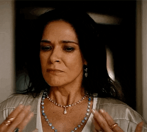 a woman wearing a necklace and earrings is making a funny face with her hands .