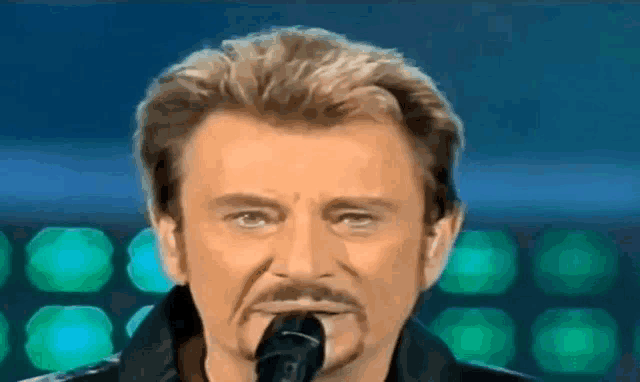 a close up of a man singing into a microphone .