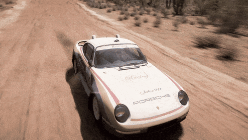 a white porsche 911 is driving on a dirt road