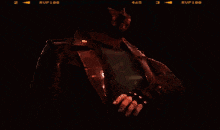 a man in a leather jacket is holding a gun in his hand in a dark room