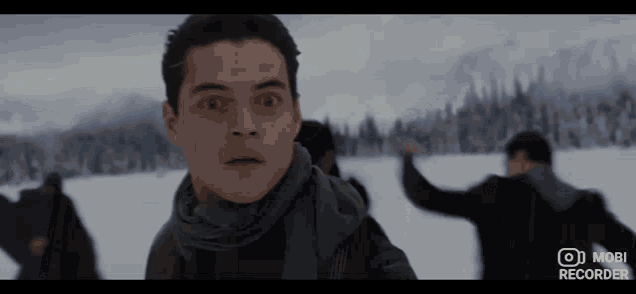 a man in a scarf stands in a snowy field with a mobi recorder on the bottom