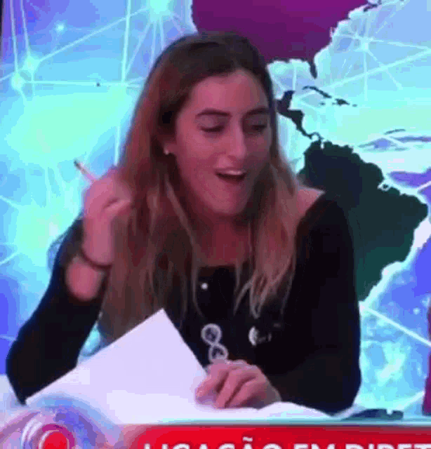 a woman is laughing while holding a piece of paper in front of a world map .