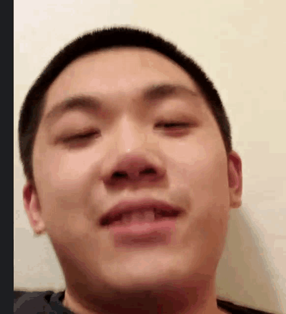 a close up of a young man 's face with his eyes closed and his mouth open .