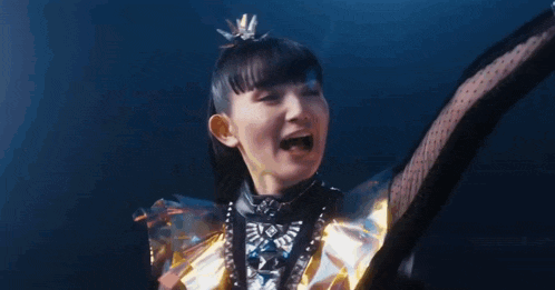 a girl in a metal outfit is dancing with her arms outstretched in the air .