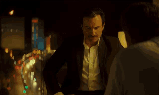 a man in a suit with a mustache is looking at another man