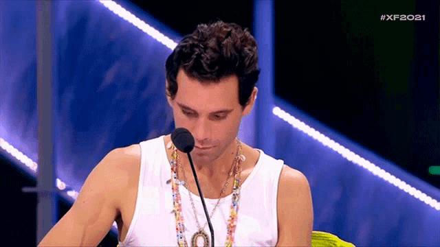 a man in a white tank top is speaking into a microphone with the hashtag xf2021