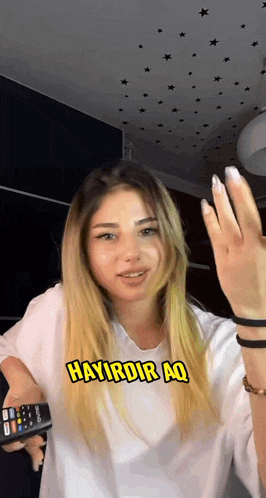 a woman holding a remote control with the words hayirdir aq written on it