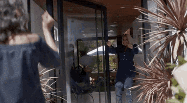 a woman is standing in front of a glass door with her arms outstretched .