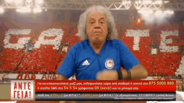 a man wearing a blue adidas shirt is standing in front of a stadium
