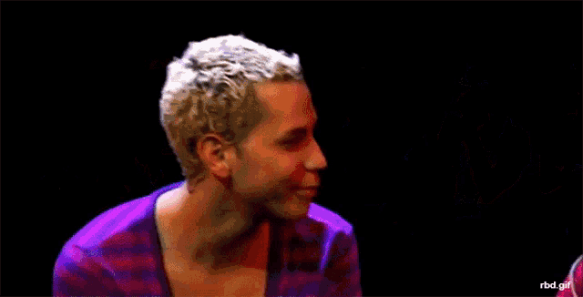 a woman is touching a man 's face with a rbd gif behind them