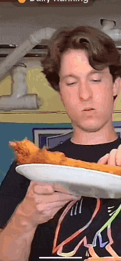 a young man is holding a plate of food in his hands .