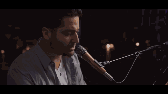 a man is singing into a microphone with a wooden handle