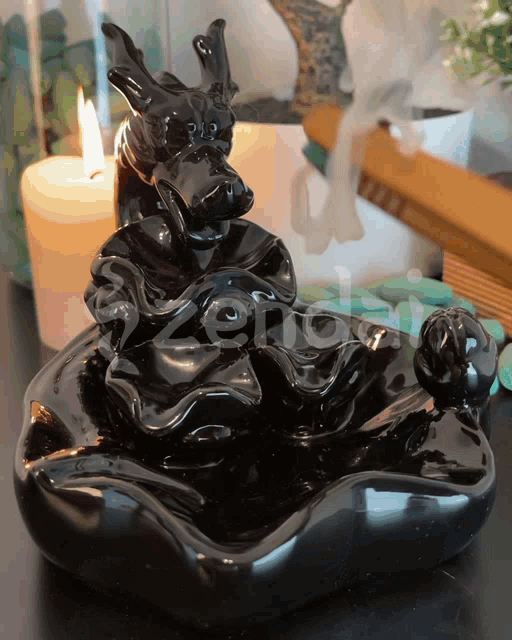 a black incense burner with a dragon on it sits on a table