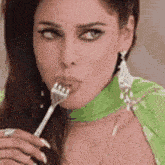 a woman in a green dress is holding a fork to her mouth .