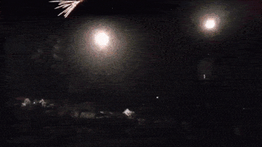 a woman stands in front of a fireworks display at night