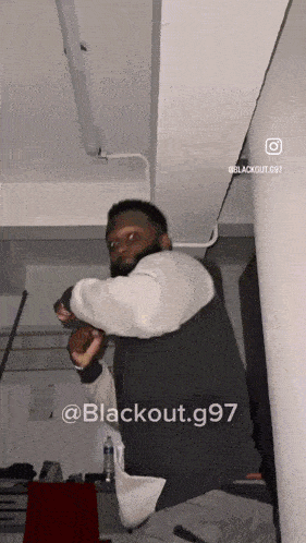 a man is standing in a room with the words blackout.g97 on the bottom right