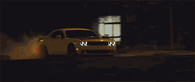 a white dodge challenger driving down a street at night