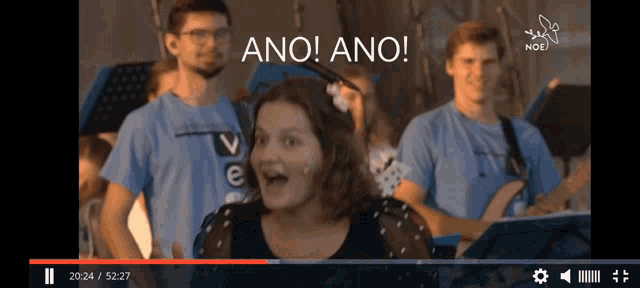 a woman singing in front of a group of people with the words ano ano written above her