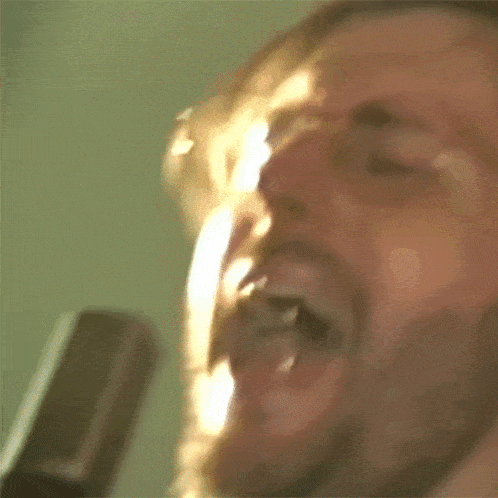 a man is singing into a microphone with his mouth open