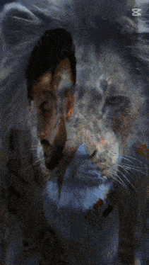 a man with a beard is holding a cat and looking at his cell phone