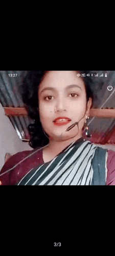 a woman in a striped saree is wearing a microphone on her neck .