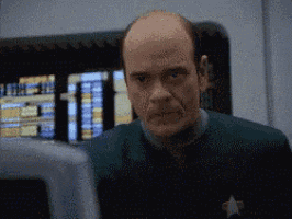 a bald man with a star on his uniform is looking at the camera