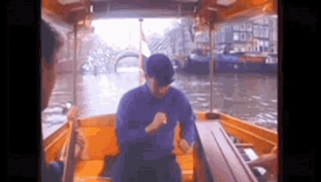 a man in a blue shirt is dancing on a boat in the water .