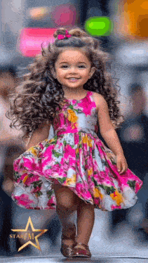 a little girl with curly hair wearing a floral dress