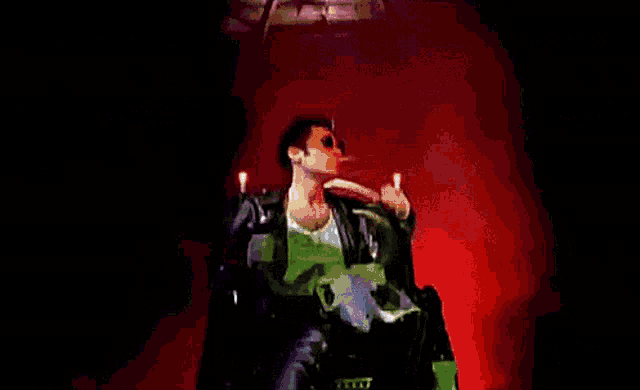 a man in a leather jacket and sunglasses is holding a skull and candles