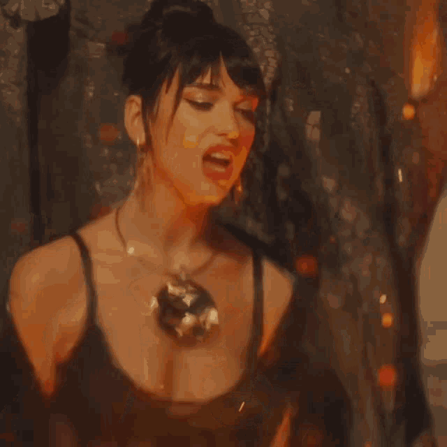 a woman in a black top is surrounded by fire
