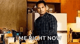 a man in a plaid shirt is standing in a kitchen with a spoon in his hand .