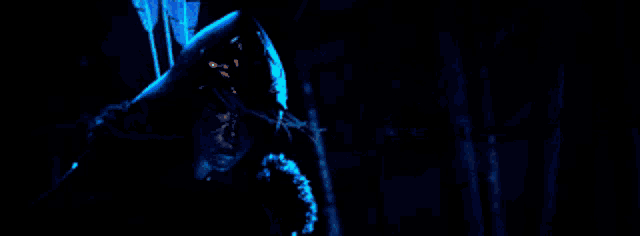 a woman is holding a bow and arrow in a dark room