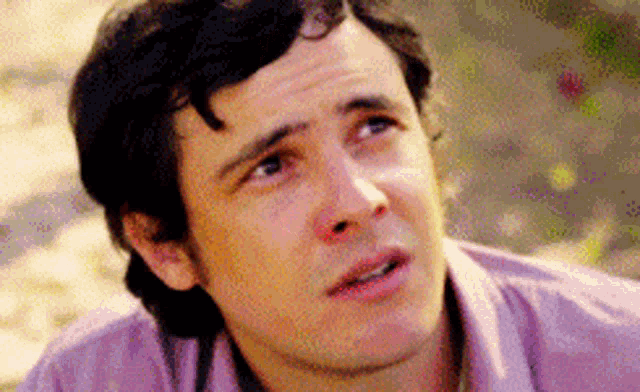 a man in a purple shirt is looking up at something