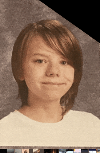 a picture of a young boy with long brown hair and a white shirt