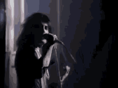 a man is singing into a microphone on stage in a dark room .