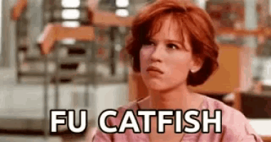 a woman with red hair is sitting at a table with the words `` fu catfish '' written on the screen .